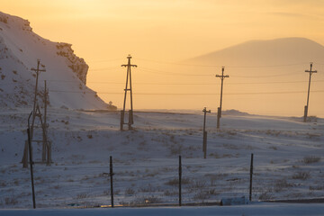 Wall Mural - Winter arctic landscape with electric poles in the snow-covered tundra on the background of mountains. Power supply in the far North of Russia. Cold weather. Chukotka, Siberia, Russian Far East.