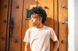 © ADDICTIVE STOCK - Gen Z man with afro hair standing by wooden door