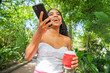 © ADDICTIVE STOCK - Young woman enjoying coffee and using mobile phone outdoors
