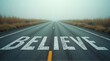 © DhanaStudio - Empty road with the word believe painted in large white letters on asphalt
