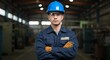 © haemye - A determined male worker wearing a blue hard hat and safety glasses stands confidently with his arms crossed in a dimly lit industrial factory setting, ready for his shift.