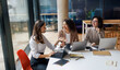 © Yaroslav Astakhov - In a modern office, three professionals are engaged in a productive discussion while using their laptops