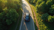 © Vadym - Top down view sleek black car drives down tree lined road, surrounded by rich green forest in sunny day. Modern vehicle on asphalt road. Travel, road trip, journey. Serene atmosphere.
