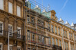 © Yahor - Renovation of historic buildings with scaffolding, showcasing detailed architecture and ornate features, under a clear blue sky, highlighting urban development and preservation efforts
