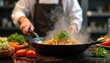 © Vadym - Pro chef prepares dish of fresh vegetables in hot skillet, surrounded by ingredients in modern restaurant kitchen. Steam rises appetizingly over culinary art. Healthy eating, cookery concept.