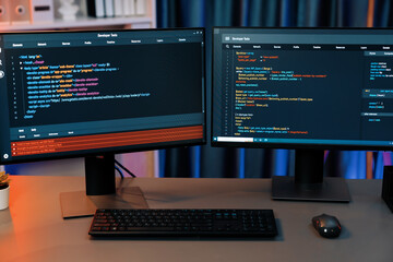Programming code on computer two screens on desktop placing working desk showing intelligent website development coder system running data online information technology at neon light room. Infobahn.