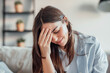 © Daniel - Unhappy young woman at home feeling sick and headache, girl touching her face feeling fatigue and exhausted. Girl with discomfort on the sofa, bad menstruation synths