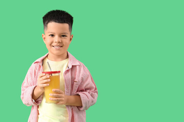 Wall Mural - Little Asian boy with cup of fresh citrus juice on green background