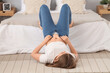 Young woman trying to button tight jeans in bedroom. Weight gain concept