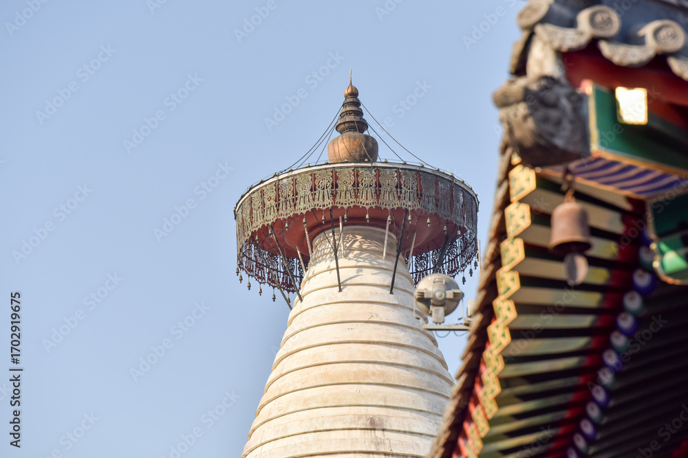 Traditional Pagoda with Ornate Roof and Bell Against Clear Sky