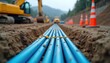 © Viktor - Close-up of blue pipes installed underground at construction site. Yellow machinery, orange safety cones visible in background. Trench dug in dirt indicates civil engineering progress on
