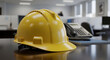 © abu - Yellow Hard Hat on Desk with Office Equipment and Blurred Background