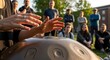 © Bagio - Group of people gathered around a handpan drum during an outdoor music workshop.