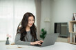 © WMSTUDIO - Asian Woman with Long Dark Hair Working on Laptop at Home Office in Bright and Modern Workspace with Plants and Natural Light