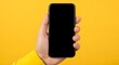 © Yassine - Hand holding black screen smartphone against bright yellow background
