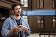 © fotofabrika - Man using smartphone with futuristic AI interface in urban setting during daylight hours
