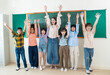 © paulaphoto - Diverse group of cheerful school children standing together in front of a chalkboard, linking arms to show teamwork and friendship.