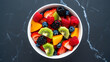 © dotmagic - Vibrant fresh fruit salad in a white bowl top down view healthy food photography delicious refreshing meal