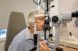 © Moon Safari - Senior woman undergoing eye examination with slit lamp for clear vision checkup at ophthalmology clinic