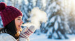 © Vasiliy - Smiling woman exhaling visible breath in the cold winter air. Happy young person in a warm hat enjoying a sunny day in a snowy forest