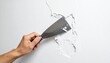 © bento - Hand applying white spackling paste to a cracked wall using a putty knife, illustrating a home repair process with focus on tool use and surface restoration.