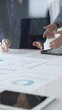 © rogerphoto - Professional team reviewing financial documents, pointing at charts on desk, collaborating to analyze data and strategize business growth. Business people concept