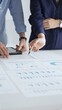 © rogerphoto - Professional team reviewing financial documents, pointing at charts on desk, collaborating to analyze data and strategize business growth. Business people concept