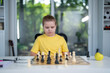 © Volodymyr - Kid think chess. Thoughtful child playing chess at desk. Clever boy learning logic with chess. Students practicing chess in classroom. Cozy home scene with kid and chessboard.