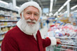 © lashkhidzetim - A smiling old man in a red Santa suit is shopping in a grocery store