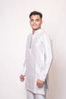 © GAJENDRRA BHATI  - Young indian man wearing ethnic attire or kurta outfit standing isolated on white studio background. Asian Fashion model looking at camera. India.