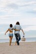 © Mirrorstudio - Young adult couple walking on a sunny beach embracing