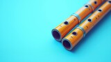 Two wooden flutes with metal bands lay diagonally on a blue background