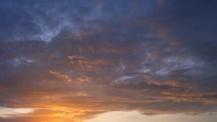 Wall Mural - A sunset sky timelapse shows golden light melting into deep clouds, symbolizing reflection, closure, transition, and the eternal cycle of endings that inspire renewal and fresh beginnings in nature.
