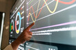 © artitwpd - Hand pointing at interactive dashboard with analytics graphs and charts on a large touchscreen display, highlighting data trends and performance metrics in a modern digital workspace.
