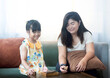 © Pheniti - Happy Asian family at home. Mother and daughter having fun playing wooden block challenge game. Playing OX TIC TAC TOE board game at home.