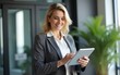 © David - Busy middle aged professional business woman using tab computer in office. Mature senior businesswoman bank manager, older female corporate executive holding digital tablet standing at work.