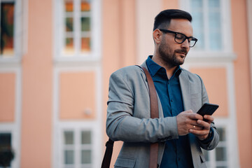 Businessman using smartphone in urban setting is reading a message