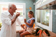 © PintoArt - Grandfather and granddaughter eating grapes in the kitchen