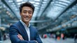 © Nick Freund - Erfolgreicher asiatischer Geschäftsmann in elegantem Anzug mit verschränkten Armen und professionellem Lächeln