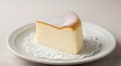© Khasani - A single slice of light and airy Japanese-style soufflé cheesecake, dusted with powdered sugar, served on a classic white plate