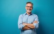 © Michelle - Happy mature man in his forties wearing casual shirt standing isolated on blue background. Smiling middle aged professional businessman looking at camera with arms crossed, portrait. High quality