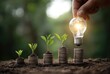 © Bagas - Stacking coins supporting small plants, with a hand holding a glowing lightbulb, illustrating growth and ideas in a lush, blurred natural background