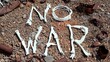 © Canary4stock - Animal bones composing the message no war laying on a gravel ground with rusty containers, remembering the horrors of war and promoting peace