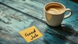 © Naknakhone - A coffee cup sits beside a yellow sticky note saying 'Good Job,' placed on a textured blue wooden surface, conveying a message of encouragement and celebration.