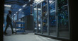 © Aleksei Gorodenkov/Stocksy - Wide view of technician walking through data center.