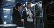 © Aleksei Gorodenkov/Stocksy - Two server specialists talk and work in data center.