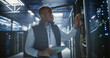 © Aleksei Gorodenkov/Stocksy - Data center technician inspects server racks, checks network cables.