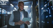 © Aleksei Gorodenkov/Stocksy - Data center technician inspects server racks, checks network cables us
