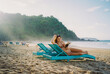 © Anna Tsukanova/Stocksy - Woman reading book on the beach laying on chaise lounge
