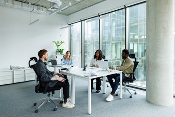 Group of smiling multiethnic architects looking at red hair colleague